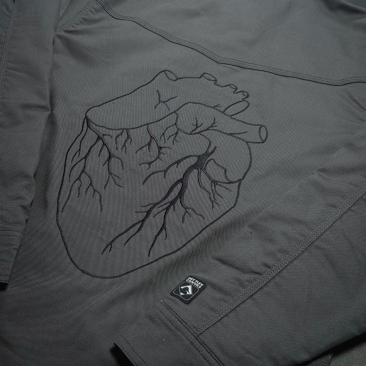 Dark gray work jacket with black embroidered anatomical heart design on chest from black gives way to blue collection
